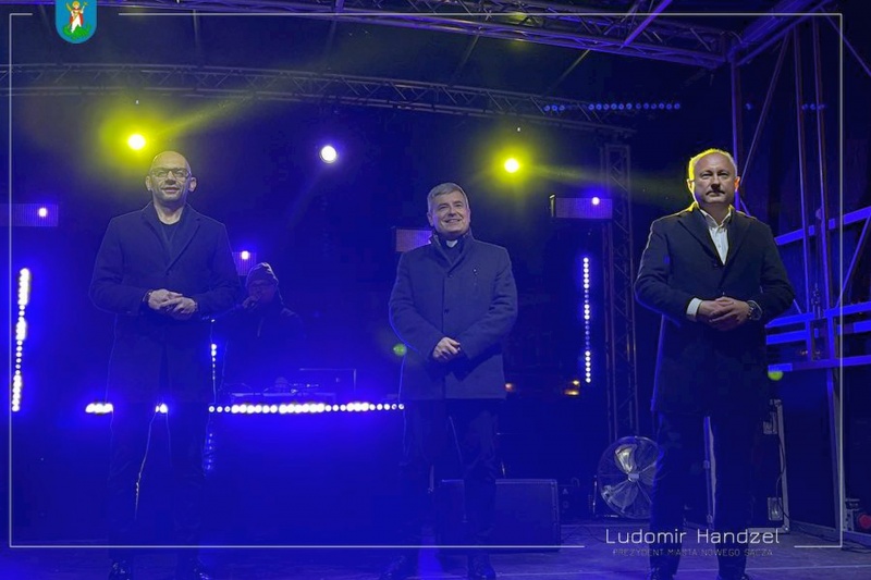 Od lewej zastępca prezydenta Artur Bochenek, ks. dr Jerzy Jurkiewicz i prezydent Ludomir Handzel składają życzenia noworoczne mieszkańcom podczas imprezy sylwestrowej na Rynku w Nowym Sączu