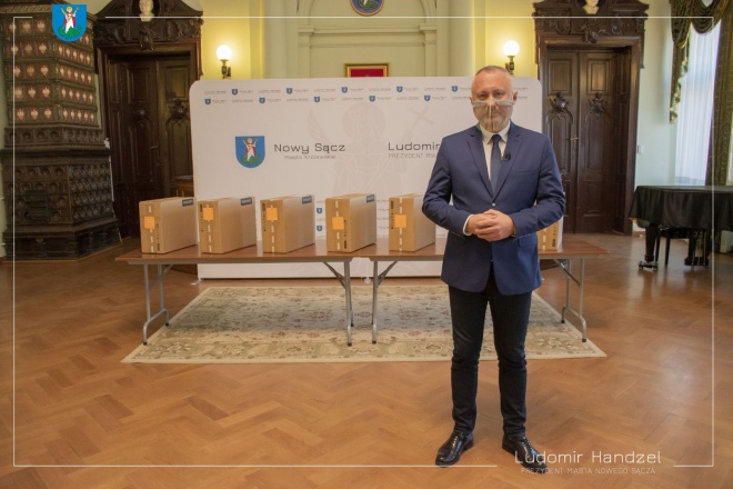 Prezydent Ludomir Handzel na tle komputerów. 