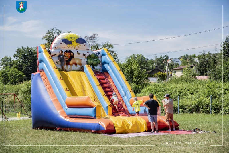 Uczestnicy pikniku podczas zabawy na dmuchanej zjeżdżalni.